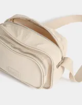 Bandolera negra de tela deportiva con bolsillo frontal con cierre, correa regulable, cierre superior y tag de goma.