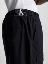 Pantalón cargo de algodón regenerativo color negro, de corte recto, con cintura elástica, bolsillos delanteros, traseros y laterales tipo cargo, puños con cordón y bragueta con cremallera.
