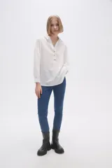 Blusa blanca holgada de poliéster con cuello camisero y mangas largas.