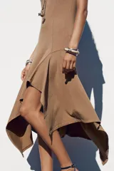 Vestido largo color marrón claro, de corte recto, con cuello redondo, mangas cortas y bajo asimétrico con volados.