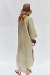 Vestido camisero largo color verde claro, confeccionado en lino. Tiene cuello solapa, escote en V, manga tres cuartos con trabilla y botón, bolsillos delanteros de plastrón, aberturas laterales en el ruedo y cierre frontal con botones.