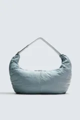 Bolso de hombro acolchado celeste de tejido técnico con cierre de cremallera. Tiene un bolsillo interior con cremallera y asa ajustable.