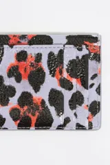 Tarjetero Bimba y Lola con estampado animal print en tonos lila, negro y naranja. Confeccionado en poliéster y poliuretano con logo metálico.
