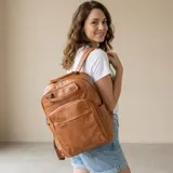 Mochila de eco-cuero color marrón, con múltiples bolsillos frontales y laterales, y asa superior.