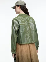 Campera corta de denim color rojo con textura metalizada, cuello camisero, cierre frontal con botones a presión, bolsillos de parche en el pecho y ruedo desflecado.