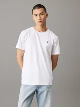 Remera blanca de algodón con cuello redondo, corte regular, mangas cortas y logo de Calvin Klein bordado en el pecho.
