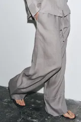 Pantalón palazzo color ladrillo, confeccionado en lino 100%, de tiro medio, cintura ajustable con cordones, bolsillos laterales ocultos y pierna ancha.