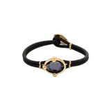 Pulsera de cuero negro con dije central de cristal facetado gris y detalles en metal dorado.