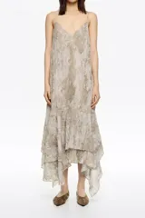 Vestido midi de tirantes finos con escote en V y estampado que simula piel de serpiente en tonos beige y gris. La falda es escalonada con volados asimétricos.