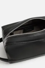 Neceser negro rectangular con cierre de cremallera y asa lateral. El interior tiene un bolsillo con cierre mediante cremallera.