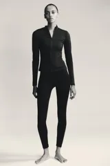 Chaqueta negra entallada de cuello alto y manga larga con cierre frontal de cremallera termosellada.