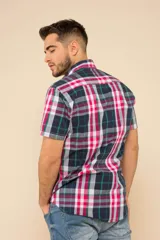 Camisa de manga corta con estampado a cuadros en tonos azul, rojo y blanco. Cierre con botones y tela ligera.