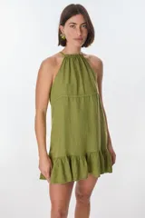 Vestido corto color beige, con escote halter, tirantes finos y falda con volados.