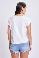 Camiseta blanca de manga corta con cuello redondo y diseño de hombros caídos (raglan), terminación deshilachada en el ruedo inferior.