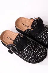 Zueco negro con plataforma, tachas plateadas y hebilla ajustable.