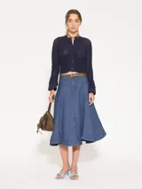 Cardigan azul marino de tejido de lino y algodón, largo hasta la primera cadera. Tiene mangas largas con puños acampanados de tela plana y cierre frontal con botones.