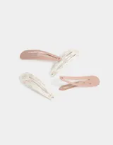 Set de cuatro hebillas para el pelo tipo tic tac, dos de color rosa pálido liso y dos de color blanco con estampado de moños rosas.