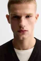 Chaleco negro de punto con cuello en V, corte cropped y sisas amplias. Tejido en hilatura de algodón con acabados en rib.