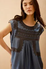 Vestido corto azul denim con bordados en hilo negro en escote, mangas y ruedo. Corte amplio y bolsillos laterales ocultos.