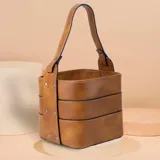 Porta termo y mate tipo balde, color negro, confeccionado en símil cuero con costuras blancas visibles. Posee una asa reforzada y una división interna.