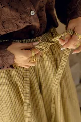 Pantalón de lana con estampado tartán en tonos beige y marrón, de corte amplio, cintura alta con elástico y lazo ajustable, y bolsillos laterales.