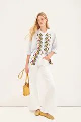 Camisa blanca de voile con rayas finas, corte amplio, cartera con botones y bordado de flores en el frente.