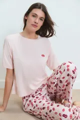 Pijama de dos piezas: remera rosa claro de manga corta con un pequeño bordado de labios en el pecho, y pantalón largo con estampado integral de labios en tonos rosados y bordó.