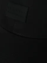 Gorro negro de algodón con visera curva y parche rectangular con logo en el frente. Ajuste trasero con hebilla metálica.