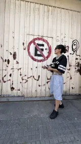 Bermuda de algodón gris jaspeado, con cintura elástica y cordón ajustable. Presenta un forro interior con estampado de camuflaje tipo bosque (Realtree) visible en el borde superior. Posee un pequeño bordado en la pierna derecha.