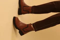 Bota corta color camel de cuero sintético, con detalle de pespuntes negros en el tobillo y cierre lateral con cremallera.