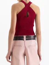 Top de punto acanalado color negro, ajustado al cuerpo y de largo por encima de la cadera. Presenta cuello redondo cerrado y breteles cruzados en la espalda. Confeccionado en hilado frío.