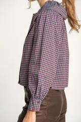 Camisa a cuadros azul y rosa con cuello babero, mangas largas abullonadas y cierre frontal con botones.