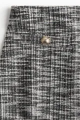 Pantalón ancho de tiro alto con elástico oculto en la cintura, confeccionado en tejido texturizado a cuadros en tonos grises. Presenta pliegues delanteros y traseros, bolsillos delanteros decorativos con botón metálico.