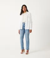 Camisa blanca de manga larga con cuello camisero, cierre frontal con botones a tono, dos bolsillos con solapa en el pecho y puños con trabilla.