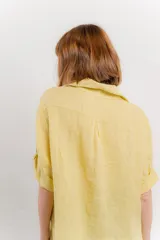 Camisa color beige de lino, con corte recto y calce suelto, cuello camisero, botones en el frente y mangas cortas con presilla y botón.