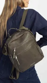 Mochila color verde oliva de símil cuero con textura. Tiene doble cierre superior, dos bolsillos frontales con cierre metálico, asa de mano rígida y correas de galón regulables.