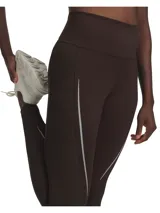 Calza larga de lycra color marrón oscuro, tiro alto, con detalles de líneas reflectivas en los laterales.