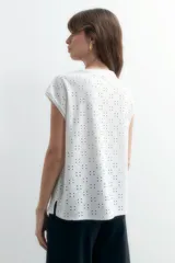 Blusa negra con bordado de flores blancas, escote en V y mangas cortas.