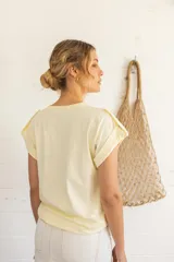 Remera blanca de corte regular, con mangas cortas y detalles de fruncido en los hombros.