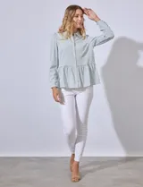 Camisa estampada a rayas verticales en tonos verde y blanco, con cuello con solapa, abertura central con botones y terminación en volado.