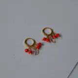 Aros dorados tipo argolla con dijes colgantes de cuentas rojas y cristal facetado.