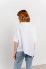 Blusa color naranja confeccionada en 100% lino, con escote en V, mangas cortas con vuelta y silueta amplia. Presenta terminación asimétrica y fila de botones decorativos en uno de los hombros.
