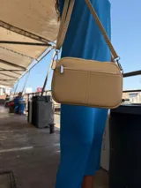 Bandolera pequeña color negro, de material símil cuero, con correa fina y herrajes plateados.