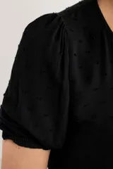 Blusa negra de viscosa al cuerpo, con mangas cortas y diseño con textura de lunares.