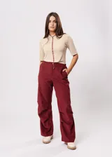 Pantalón bordeaux de corte recto, con bolsillos en los lados y diseño suelto.