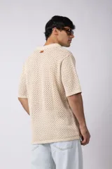 Camisa negra tejida de manga corta, con calado aireado, cuello tipo bowling y botones al tono. Diseño de corte relajado.