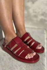 Sandalias bajas de cuero color suela, con tiras anchas entrecruzadas y hebilla lateral.