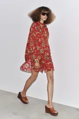 Camisa larga de algodón con estampado floral en tonos rojos, marrones y verdes. Tiene cuello solapa, manga larga con puños y bajo redondeado.