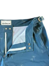 Short de baño azul con estampado de palmeras en tono gris, con bolsillos laterales y traseros, y ajuste lateral con hebilla metálica.