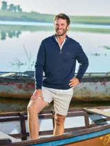 Sweater azul marino de punto, con cuello alto y medio cierre con cremallera. Tiene mangas largas y logo bordado en el pecho. Corte clásico.